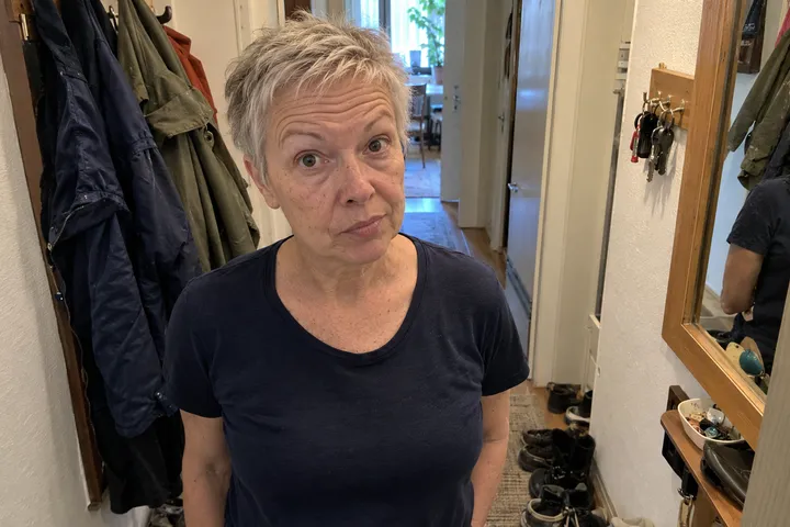 Frau mit kurzen grauen Haaren zieht im Flur vor dem Spiegel die Augenbrauen hoch